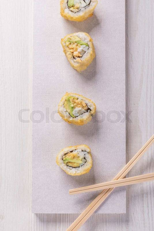 four sushi rolls with some wooden chopsticks, food in studio, delicious traditional dish