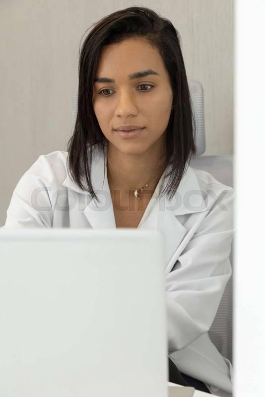 doctor with short hair sitting at her office desk working on her computer