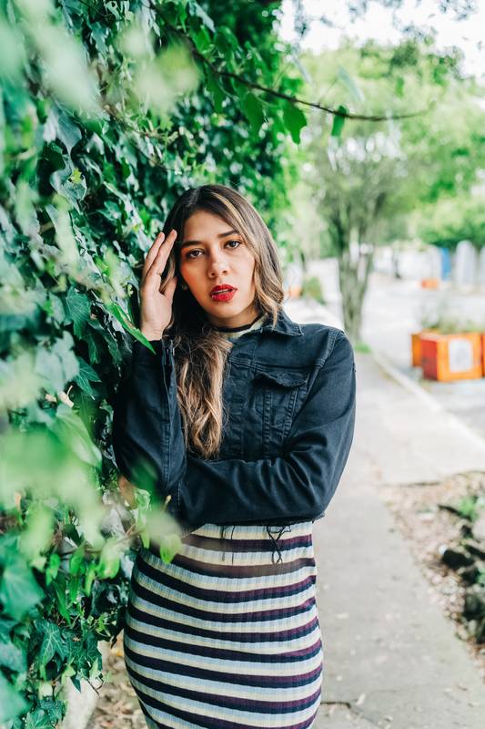 in the city street a young latin woman with long blonde hair, wears makeup with red lips and fashionable clothes