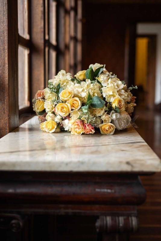 arrangement of yellow and white roses resting on a marble table