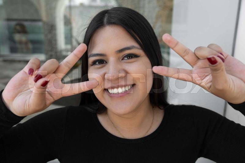 woman with love and peace symbol on her fingers, latin person , happy life