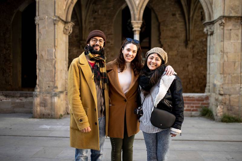 portrait of multiracial group of friends looking at camera. Three happy young adults standing in an ancient city. Holidays, friendship, cheerful concept