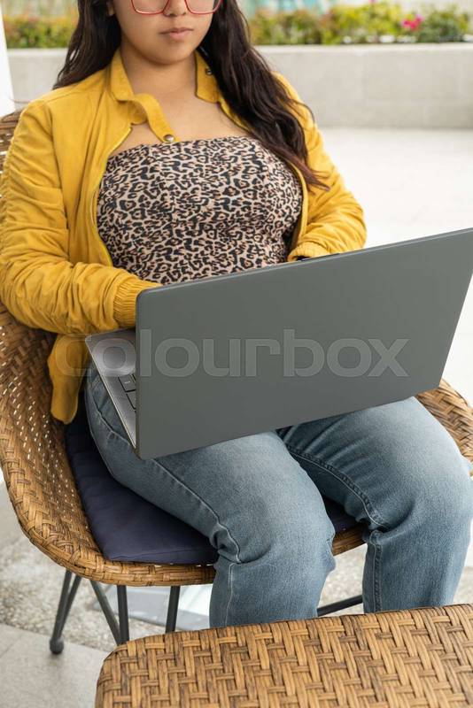 student sits in the university library, working diligently on her laptop