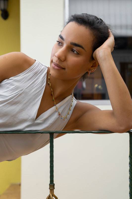 ttractive young brunette woman, wearing a necklace and earrings resting with one hand on her head