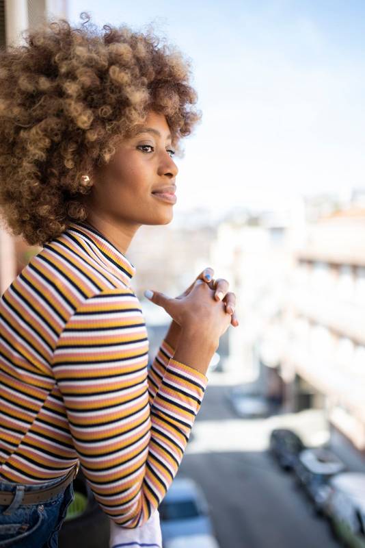 Side view of a confident woman looking away in a balcony. Portrait of a hopeful girl looking at the city from a window.