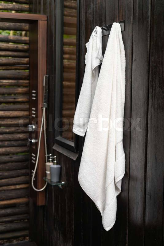 Two white towels hang neatly on a wall inside a dark wood bathroom