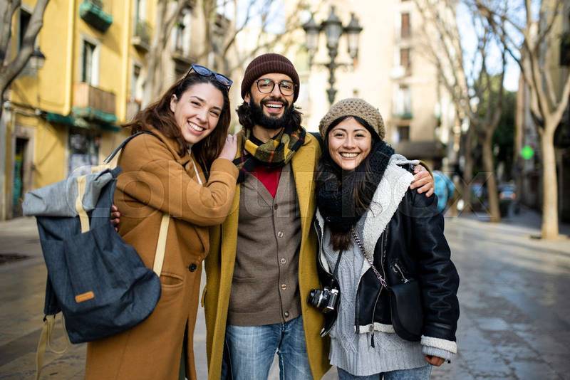 Portrait of three happy tourists standing on the street and looking at camera. Group of travelers enjoying a trip in Barcelona