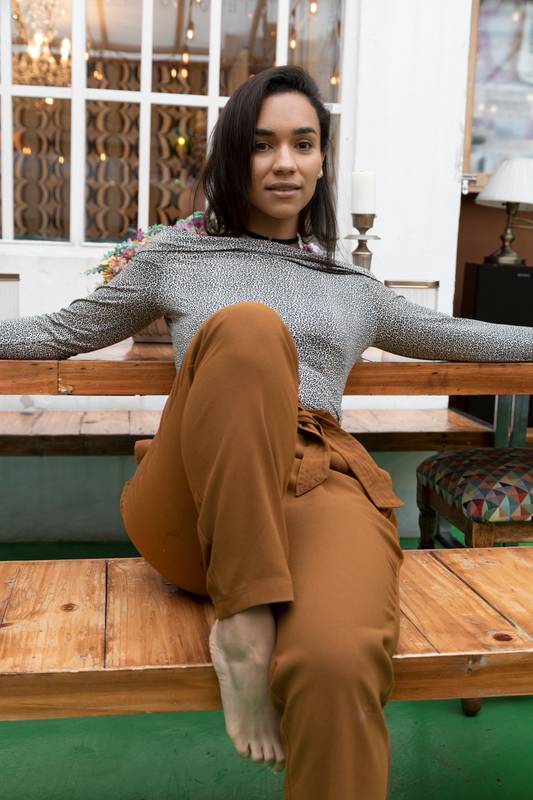 sitting on a wooden bench, wears comfortable clothes and is barefoot, fashion and modern lifestyle