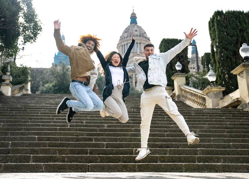 Three young diverse people jumping on a stairs. Multiracial group of successful people jumping together in the park.