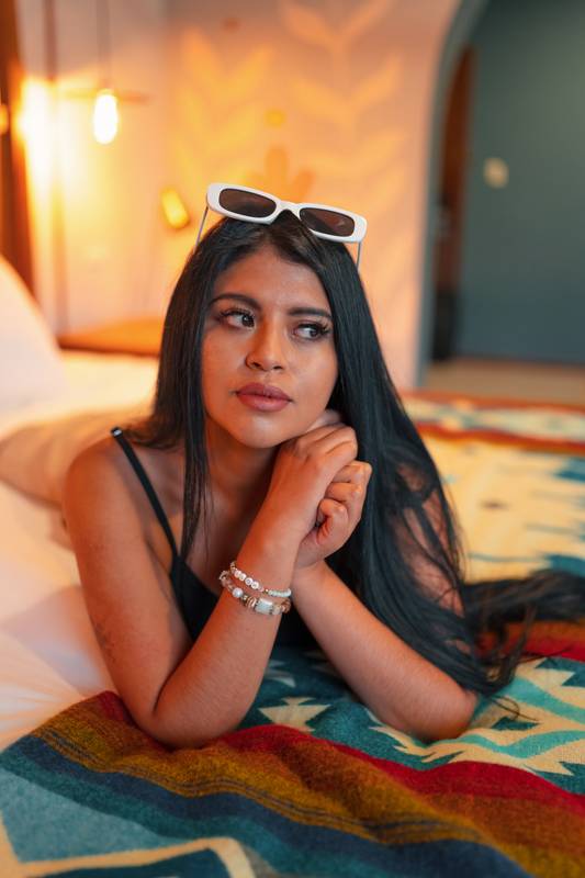 resting lying on a bed a young woman with black hair and makeup, model lifestyle