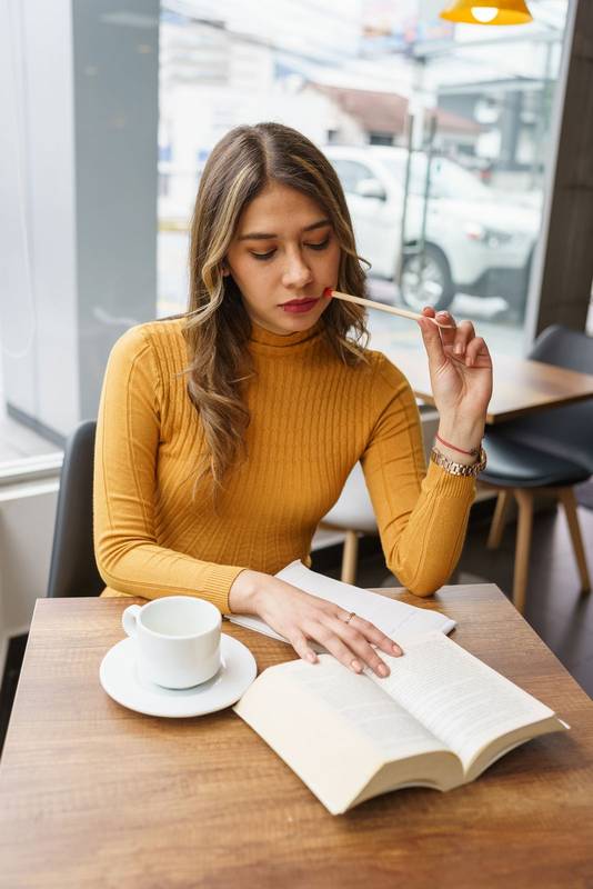 workplace with young latin woman with long blonde hair sitting thinking, hot drink