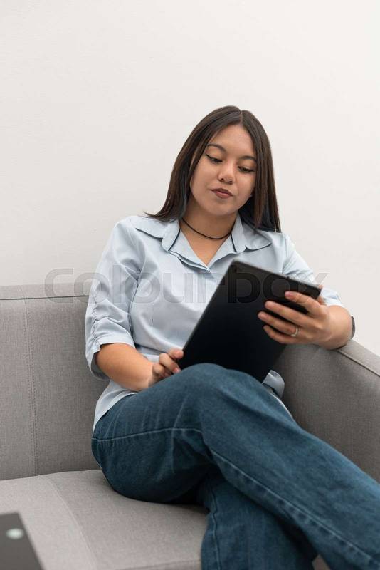 woman focused on reading from a tablet, portraying a modern work