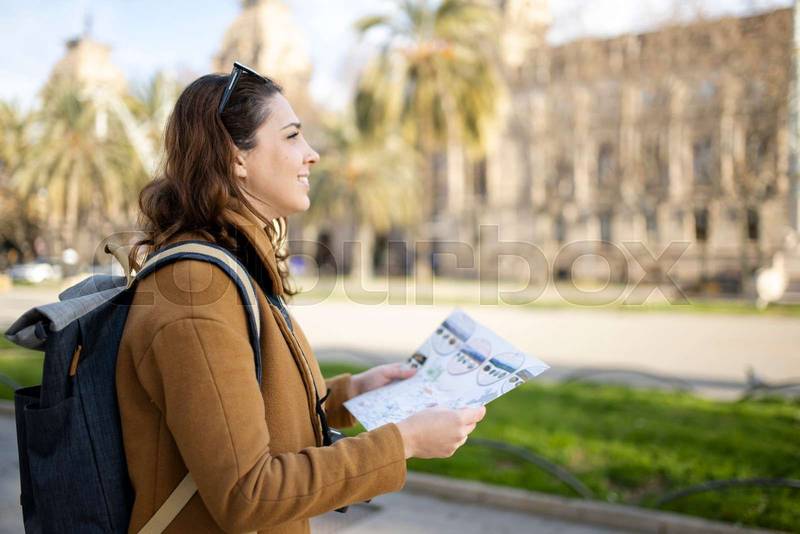 happy traveller woman looking a map outdoors. cheerful young female on vacations.