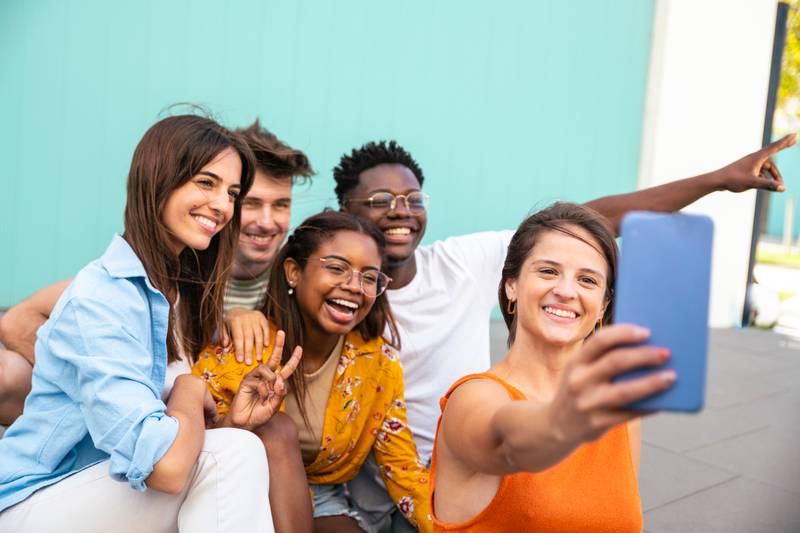 Multiracial group of friends making a selfie with phone in the university - friendship, happiness and joyful concept