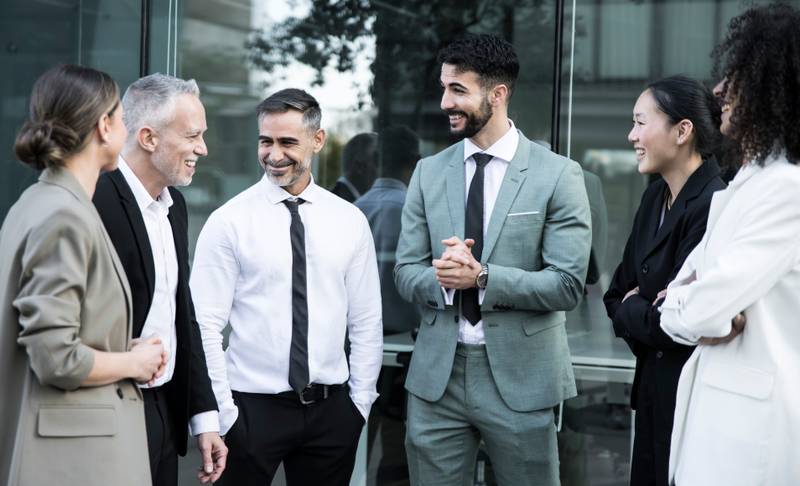 Group of business people group having a casual meeting outdoors. Office colleagues standing in the street discussing and smiling.