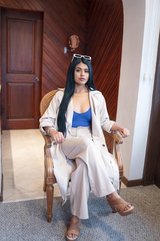 woman sitting resting on a chair, she wears shirt, light clothes and sunglasses