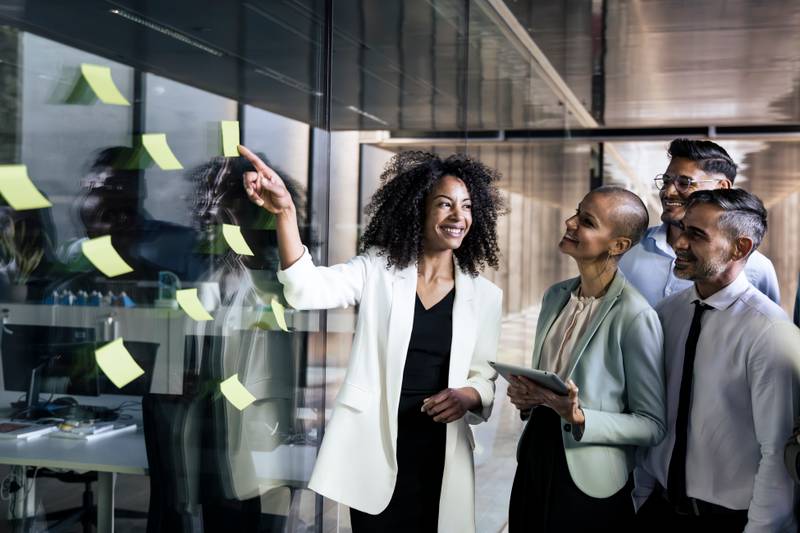 Group of business people doing presentation using post it. Businesswoman leading a team meeting