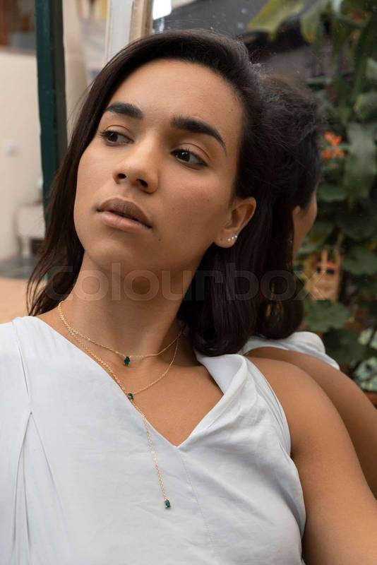 attractive young brunette woman posing next to a mirror