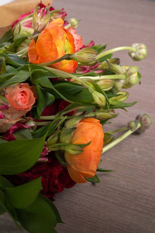 different types of flowers and leaves wrapped in decorative paper making a bouquet