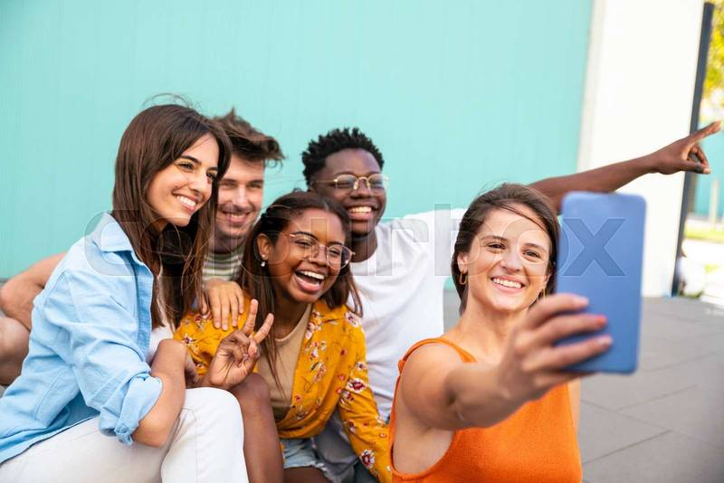 Multiracial group of friends making a selfie with phone in the university - friendship, happiness and joyful concept