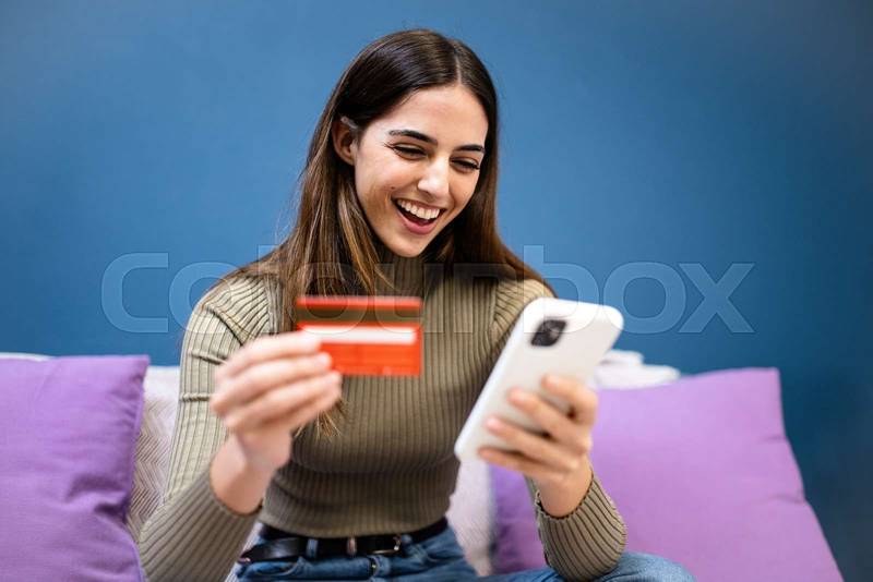 happy young attractive woman shopping online with a laptop computer using a credit card. e-commerce, business concept
