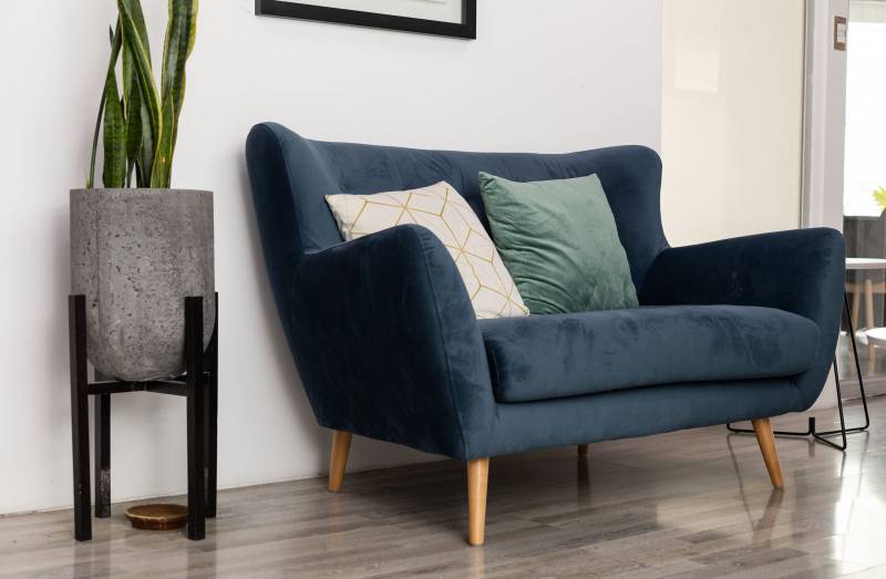 blue sofa featuring natural wooden legs in a bright, modern living space