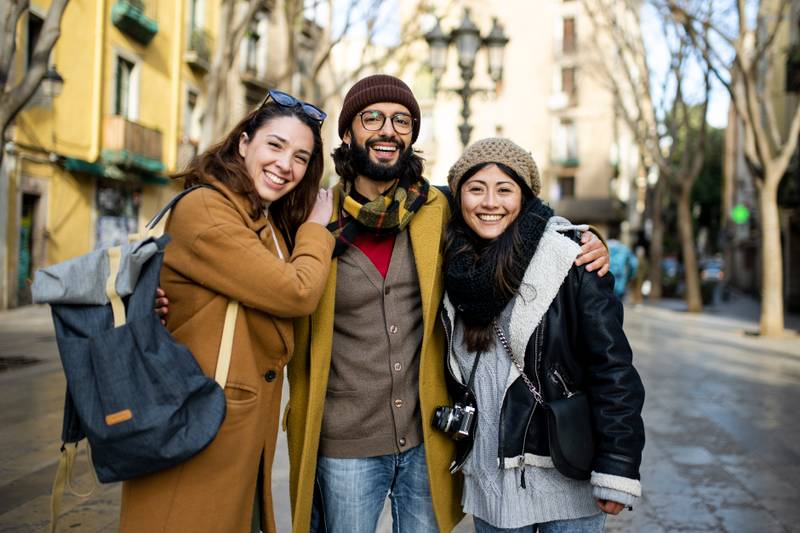 Portrait of three happy tourists standing on the street and looking at camera. Group of travelers enjoying a trip in Barcelona
