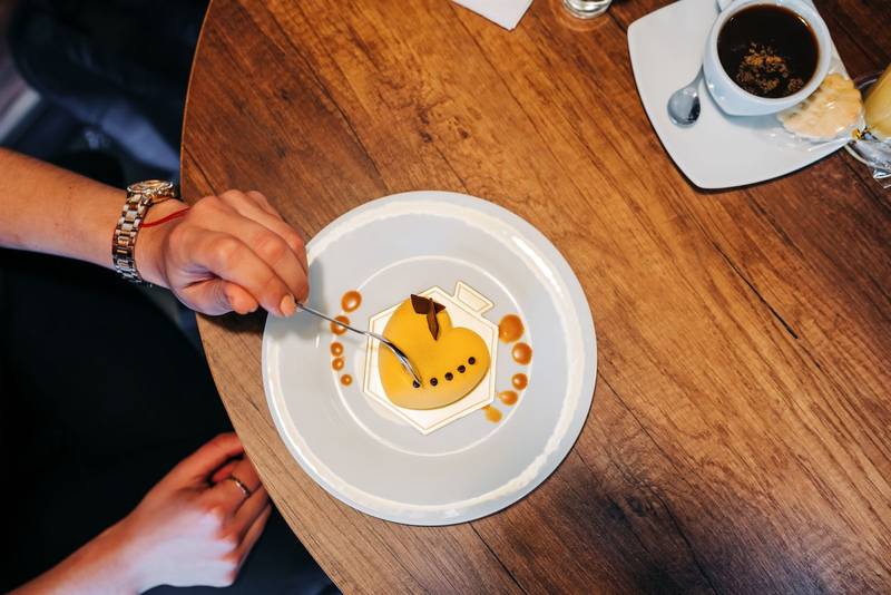 person hand holding a spoon eating a heart shaped cake