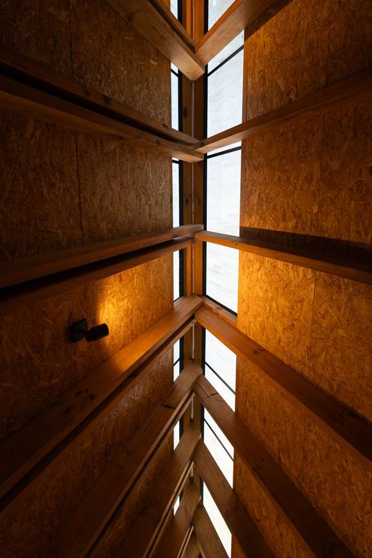 Slanted skylights in a triangular wooden roof let soft sunlight stream into the glamping space