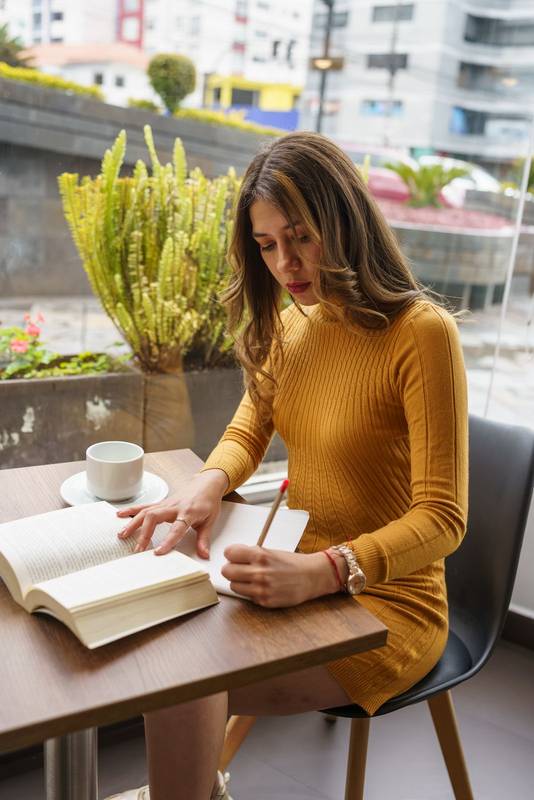 reading a book and using a pencil to make notes, cup of coffee on the table, student work