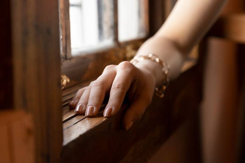 elegant nails, wears a gold bracelet, the arm is close to a wooden vein